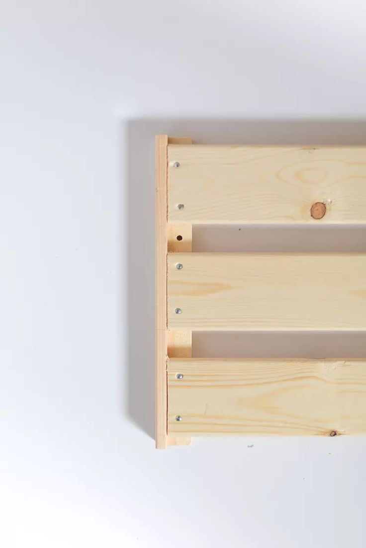 an empty wooden shelf with two pegs on it