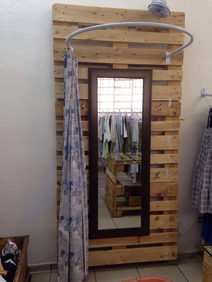 a room that has some kind of wooden structure in the corner with clothes hanging on it