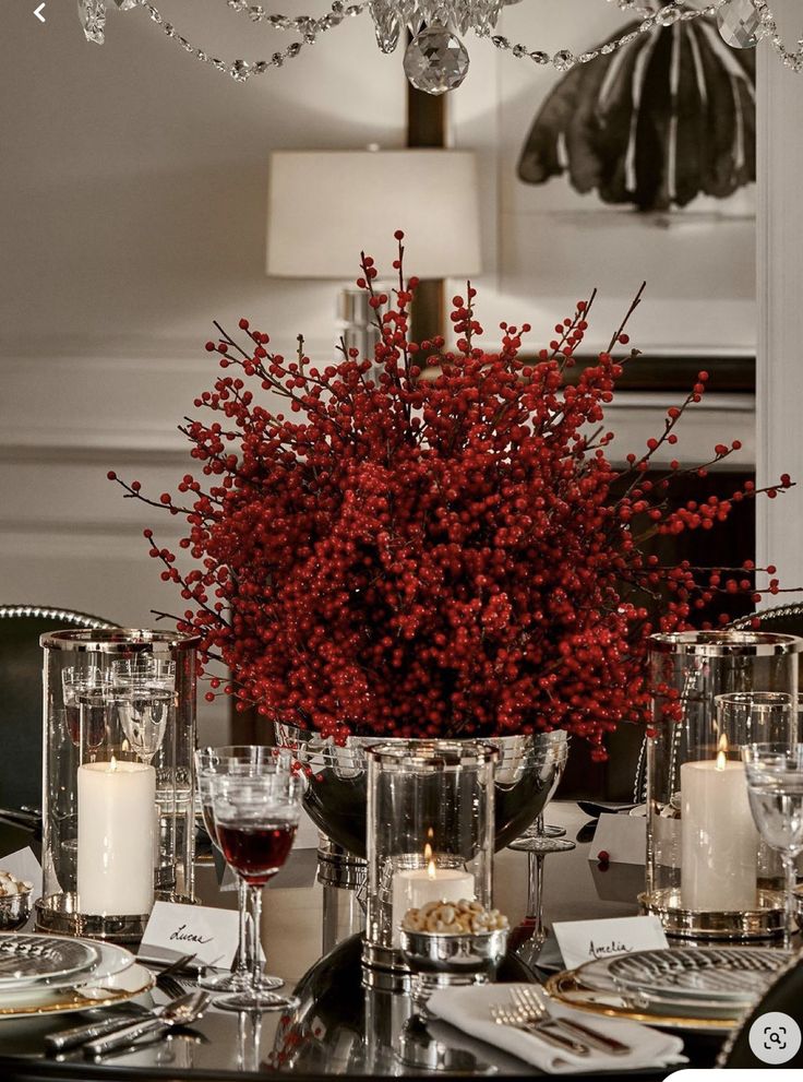 a dining room table set with candles, plates and flowers in the centerpieces