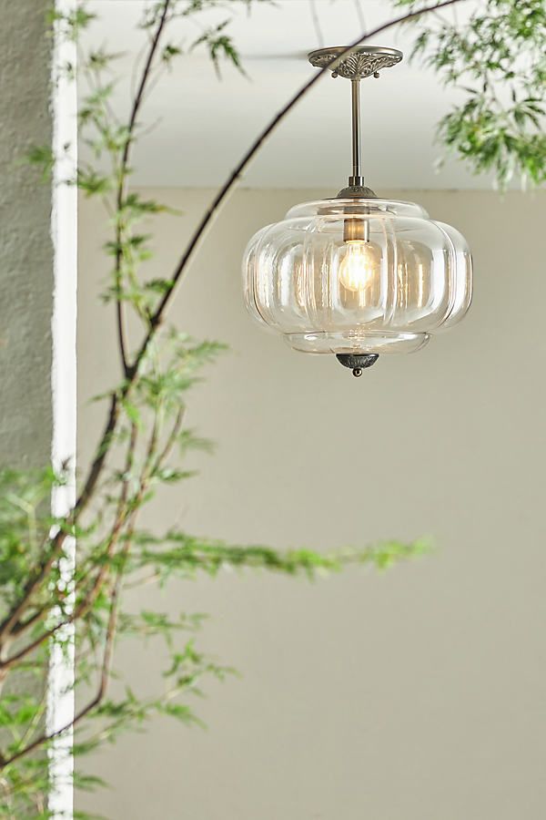 a light fixture hanging from a ceiling in a room with white walls and green plants