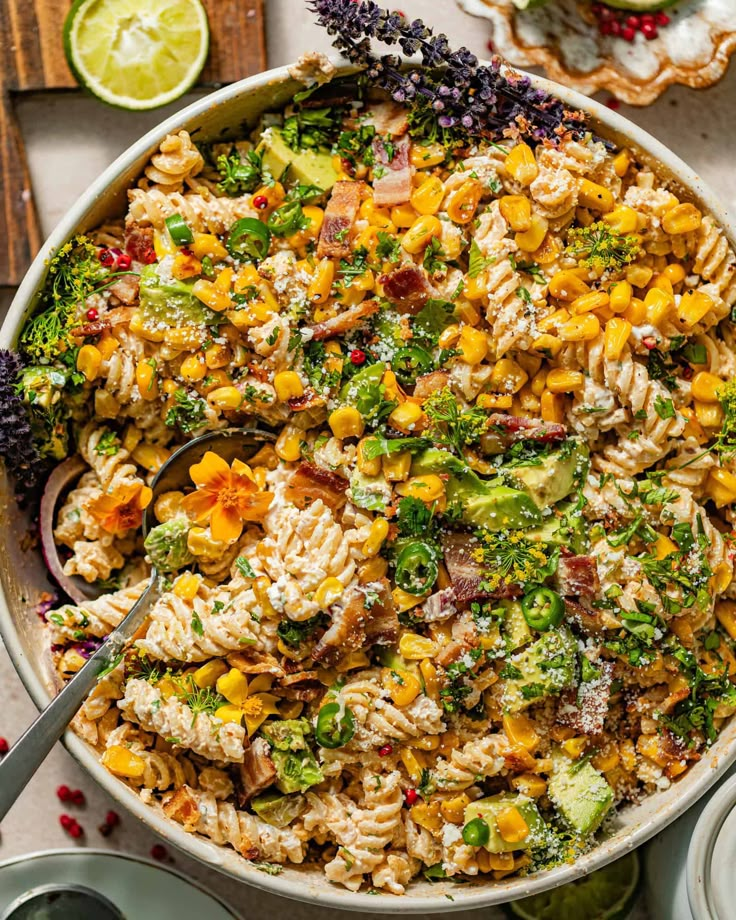 a bowl full of pasta salad with broccoli, corn and other toppings