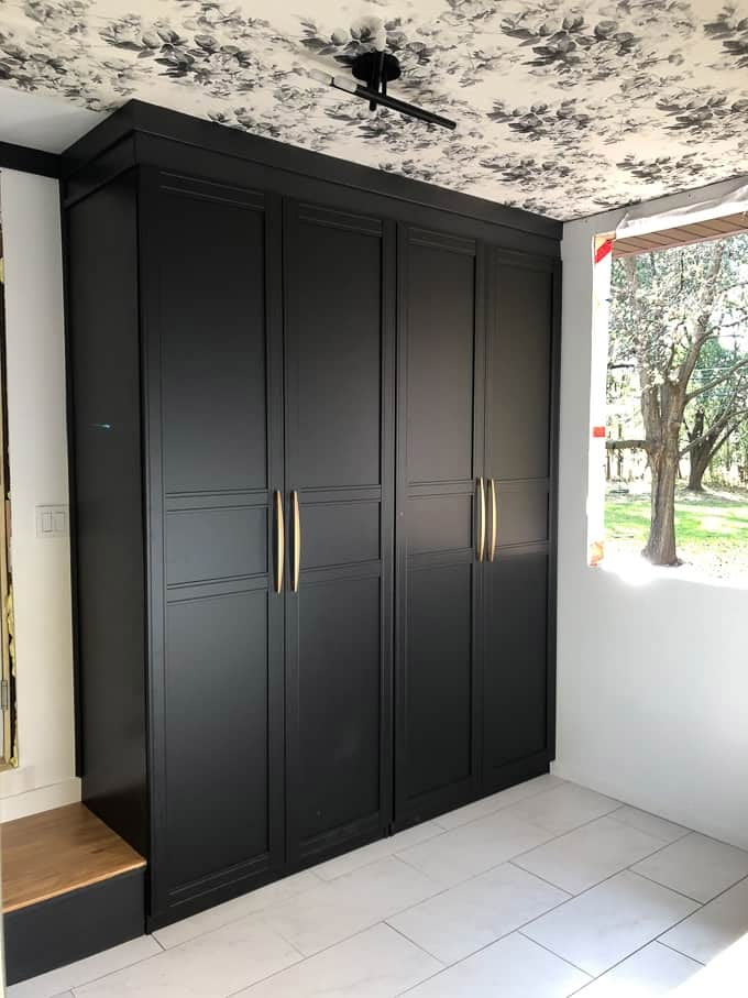 an empty room with black cupboards and white tile flooring in front of a window