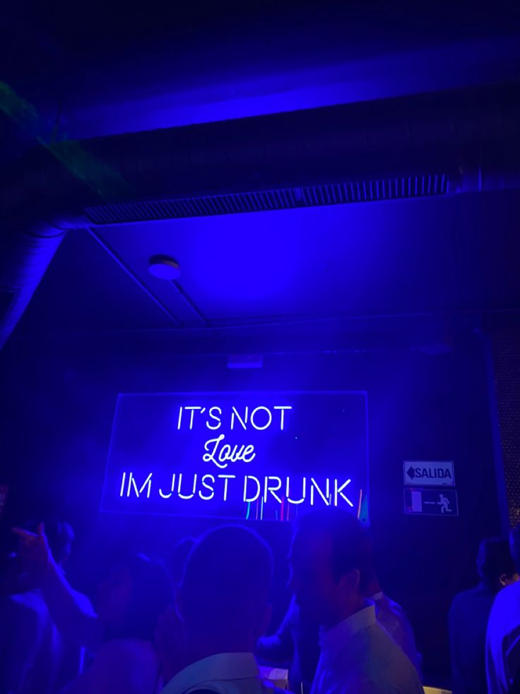 people are standing in front of a neon sign that says it's not love i'm just drunk