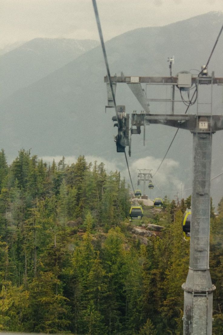 a ski lift going up the side of a mountain with trees in the foreground