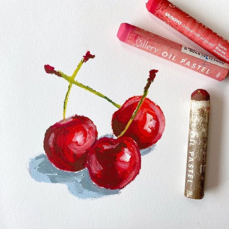 some crayons are next to two cherries on a piece of paper