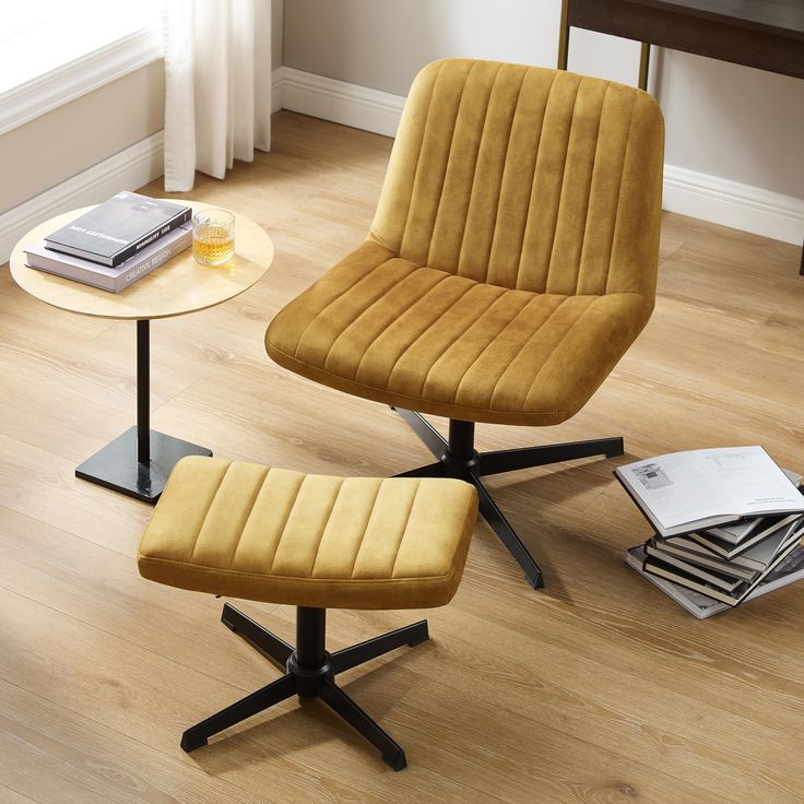 two chairs and a table with books on it in a living room next to a window