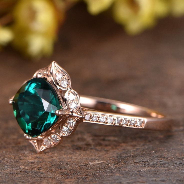 a close up of a ring with a green stone and white diamonds on the side