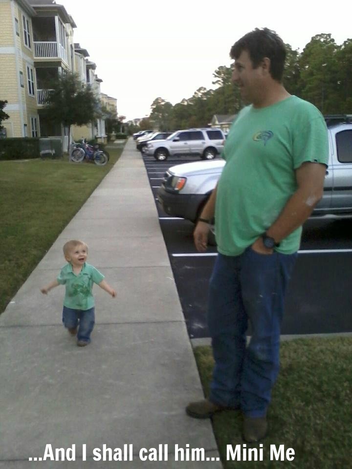 a man standing next to a sidewalk with a little boy walking down the side walk