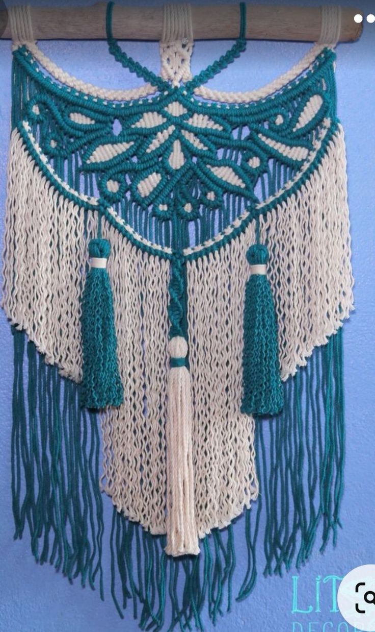 a green and white macrame hanging on a wall next to a blue wall