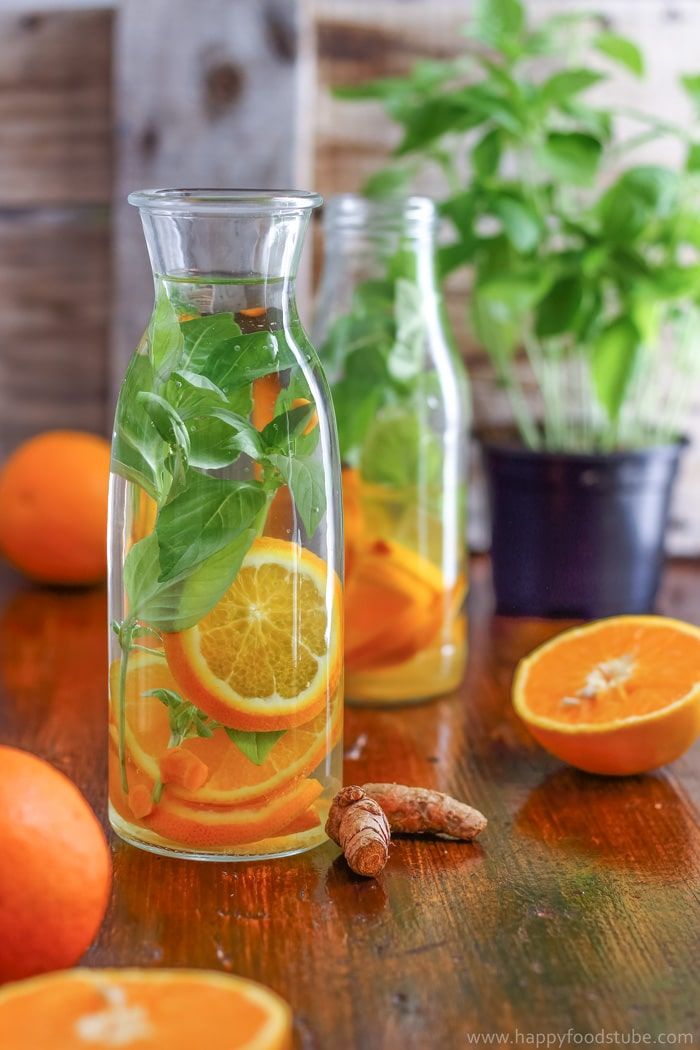 oranges, lemons and basil in glass bottles on a table