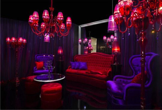 a purple and red living room with chandelier, couches, and chairs