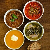 four bowls of soup and bread on a table