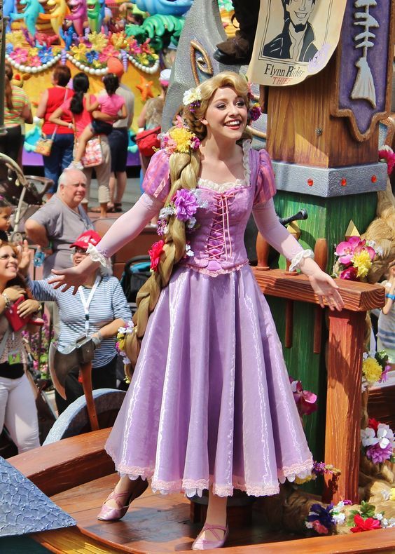 a woman in a purple dress standing on top of a wooden boat at a carnival