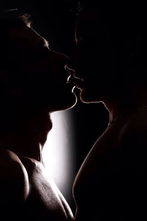 two men are kissing in the dark with their heads touching each other's noses