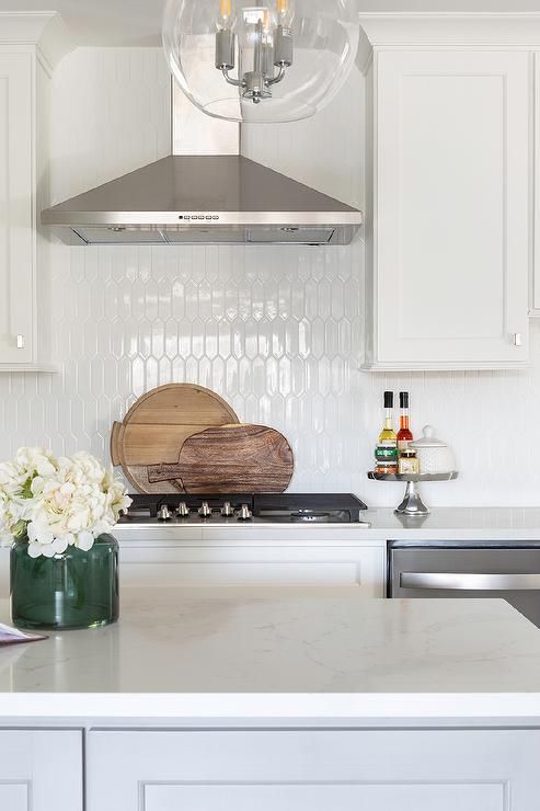 a kitchen with white cabinets and marble counter tops, an island in the middle has a wooden cutting board on it