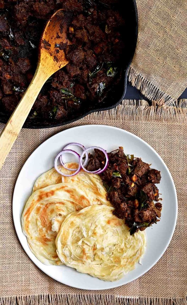 some food is on a white plate with a wooden spoon and brown table cloth next to it