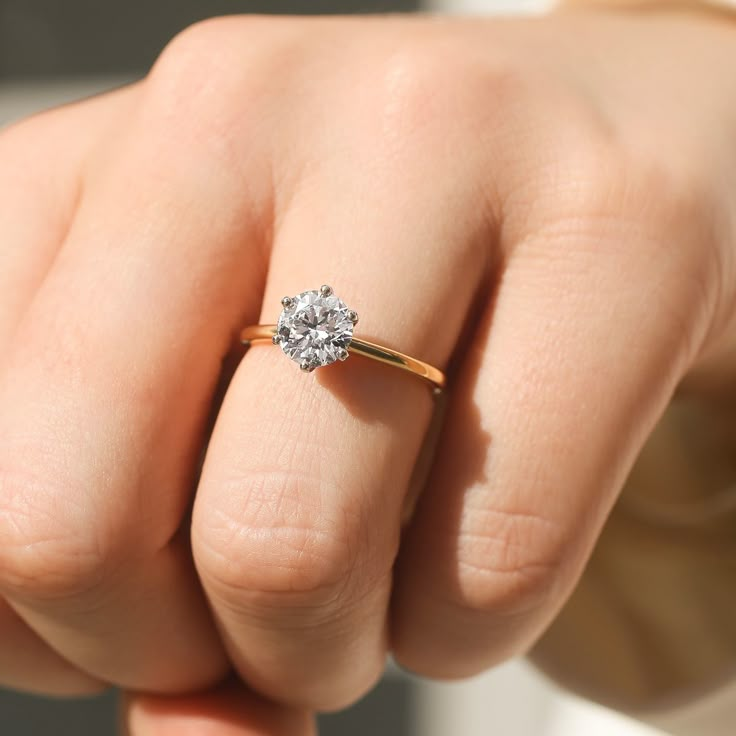 a woman's hand with a diamond ring on her finger, showing the center stone