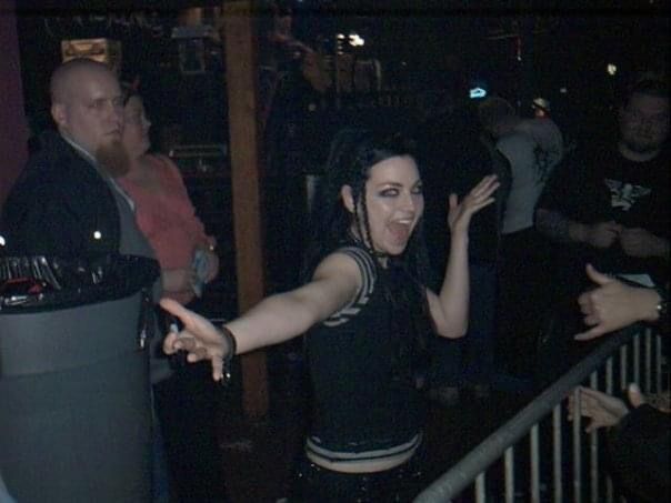 a woman standing in front of a metal railing with her arms out and hands outstretched