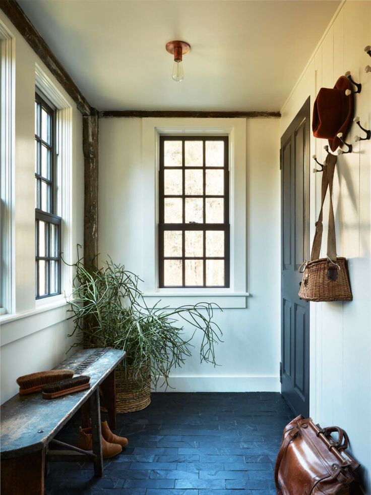 a room with a bench, window and potted plant on the wall next to it