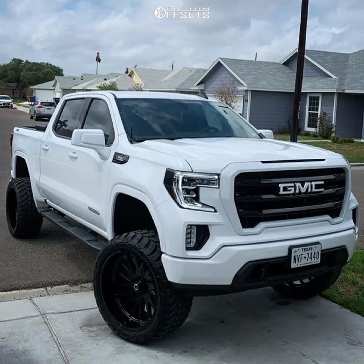 the white truck is parked on the side of the road in front of some houses