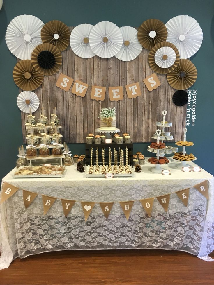 a table topped with desserts and cupcakes next to a wooden wall covered in paper fans