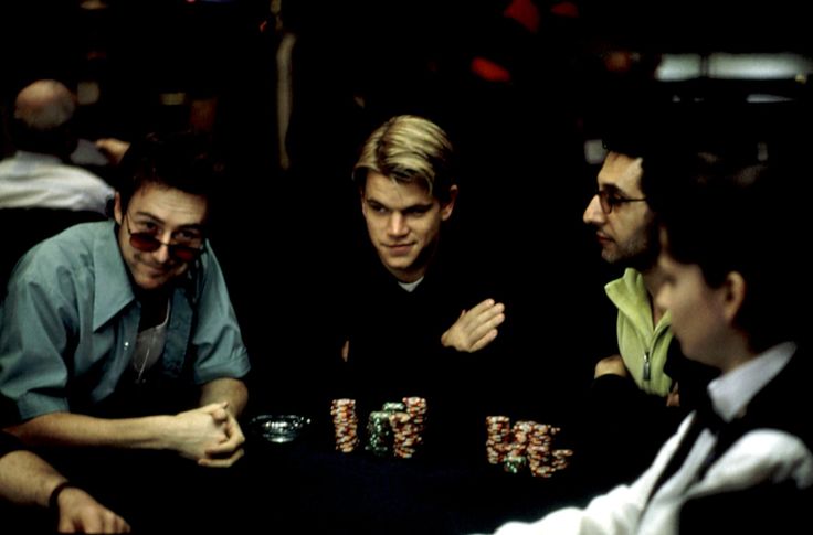 three men sitting at a table with poker chips in their hands and one man holding his hand out