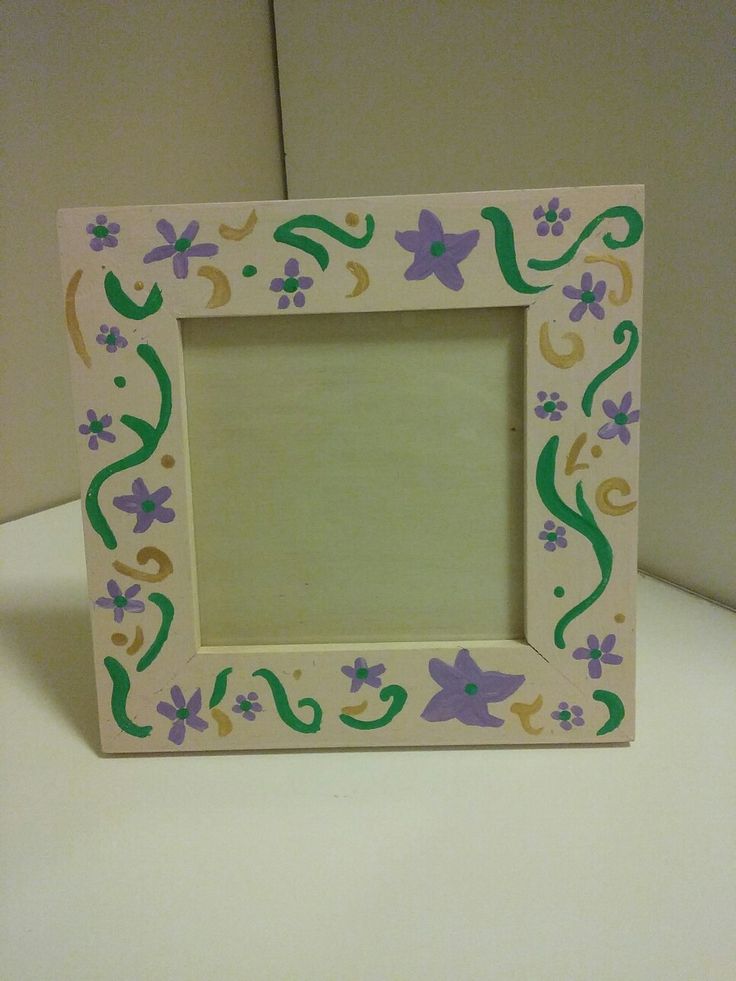 a small wooden frame with flowers and vines painted on the outside, sitting on a table