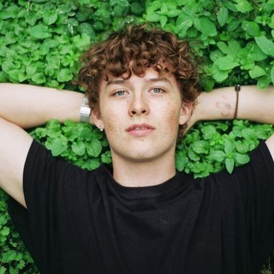 a young man laying in the grass with his hands behind his head