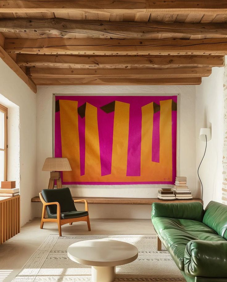 a living room with green leather couches and a large painting hanging on the wall