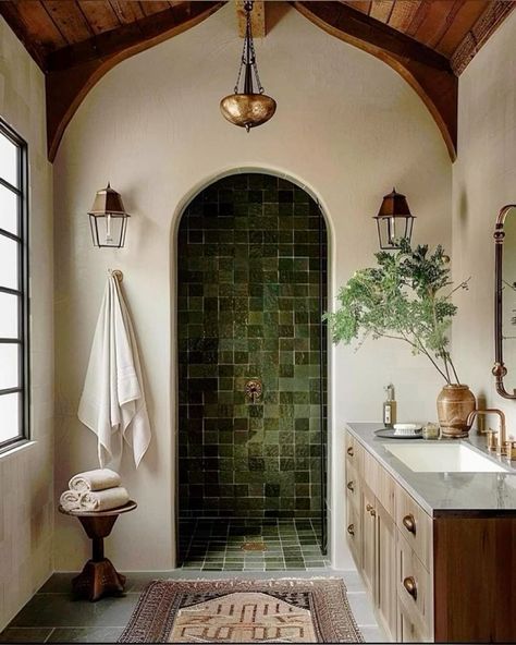 a bathroom with a green tile shower and double sink vanity, along with an arched doorway