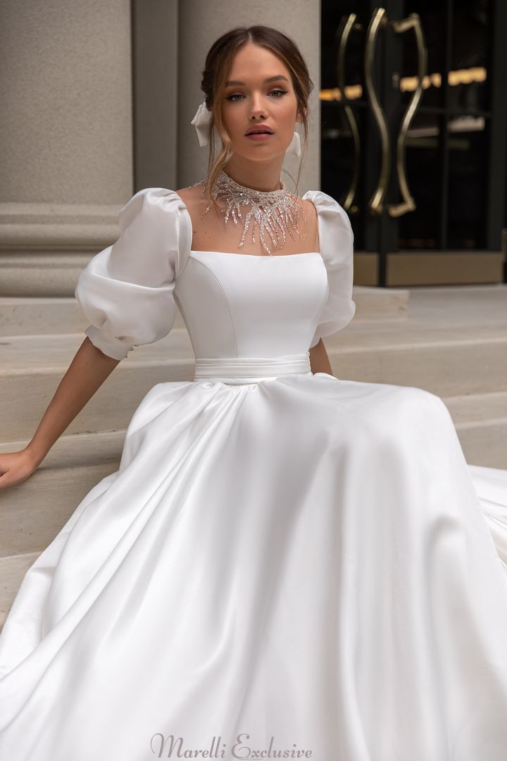 a woman in a white wedding dress sitting on the steps wearing a necklace and earrings