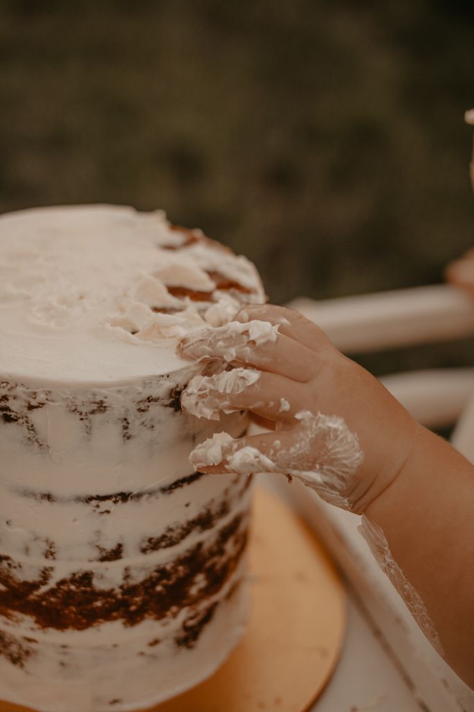 a small child holding onto a frosted cake