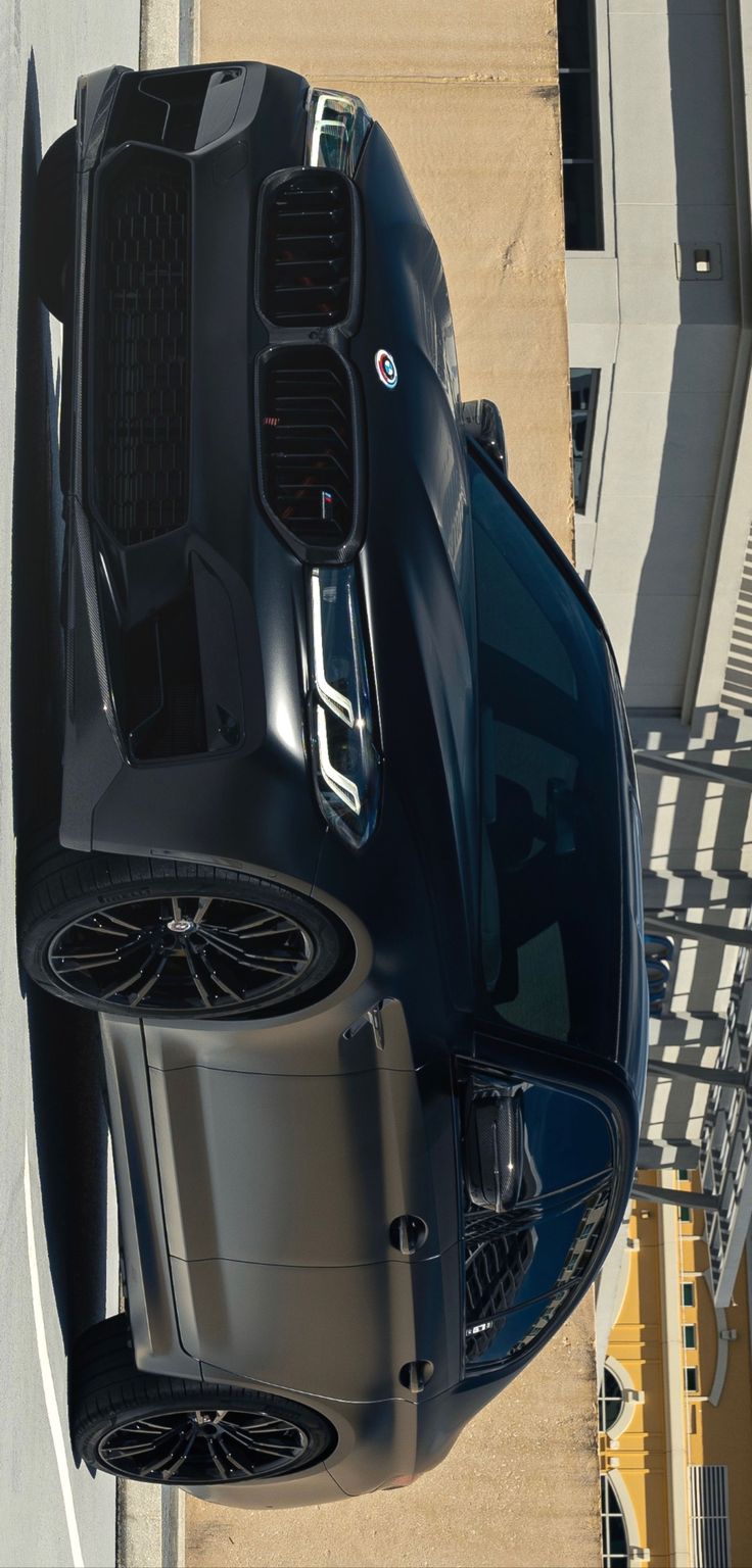 the top view of a black sports car parked in front of a building with its hood up