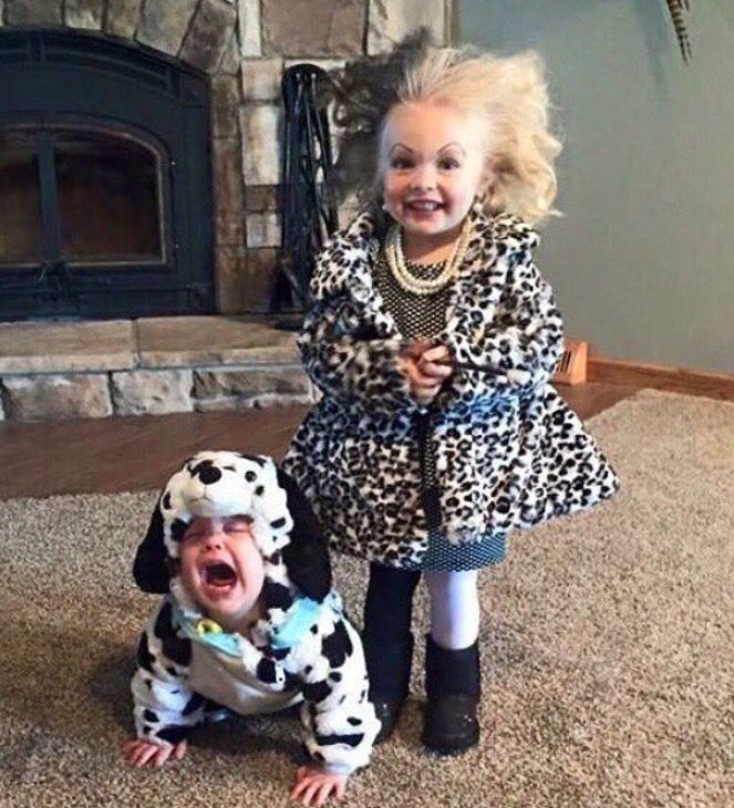 two children dressed up as dalmatian dogs in front of a fireplace