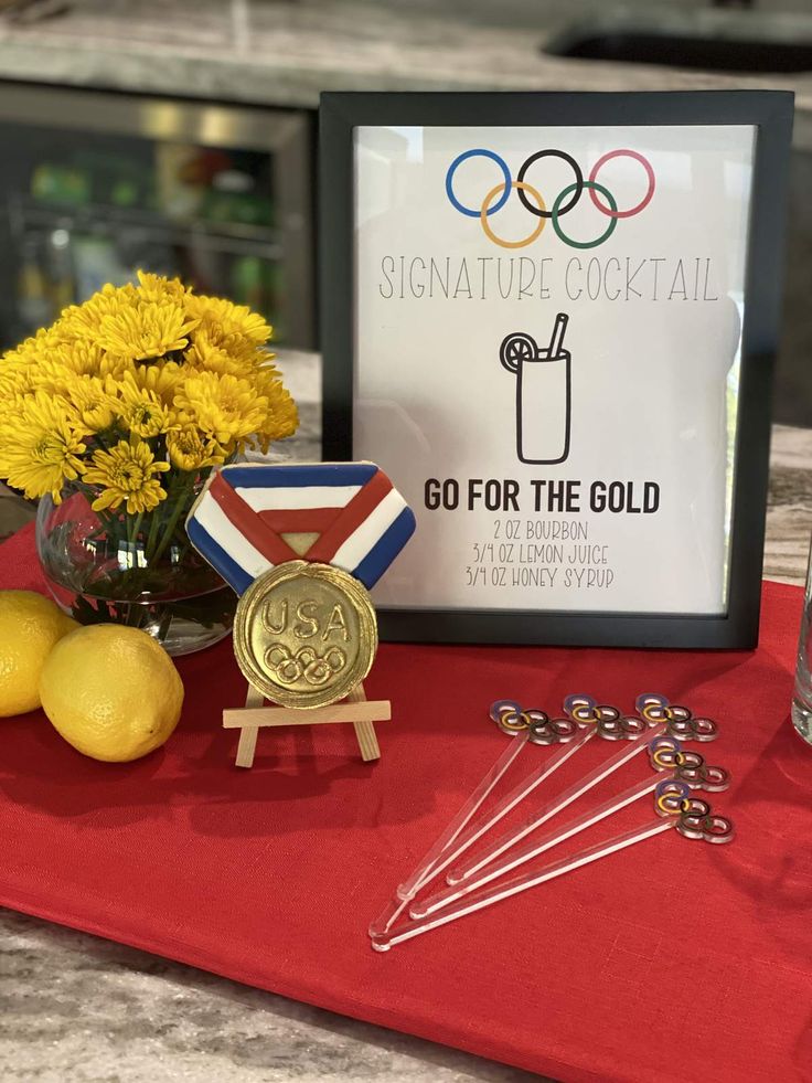 a table with medals, lemons and flowers on it next to a sign that says go for the gold