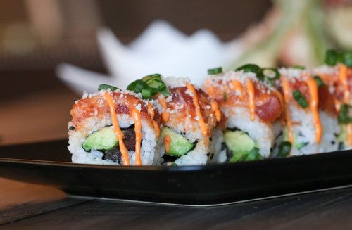 sushi rolls with sauce drizzled over them on a black platter