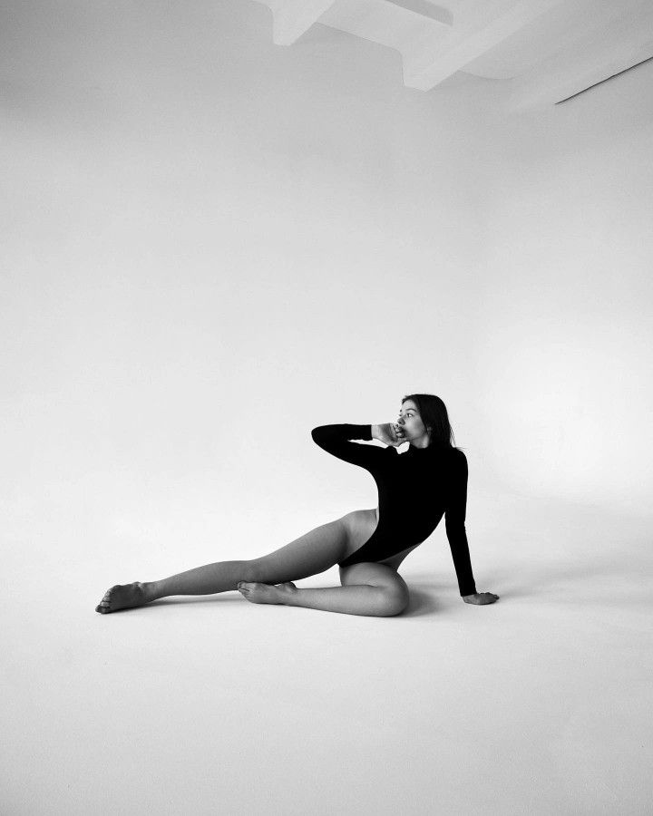 a woman sitting on the floor with her legs crossed in front of her face and arms behind her head