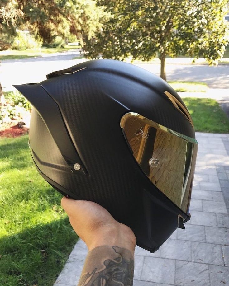 a person wearing a motorcycle helmet on their hand and holding it up to the camera