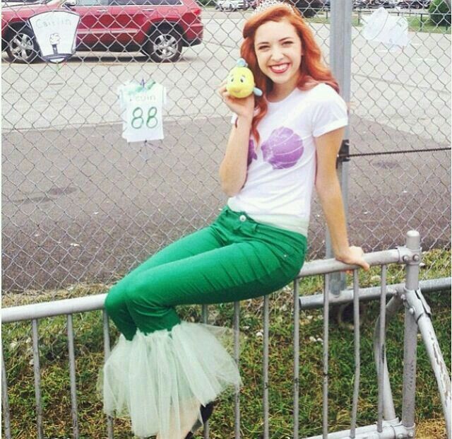 a woman with red hair is leaning on a fence and holding an apple in her hand