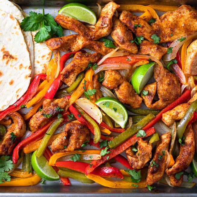 chicken fajitas with peppers, onions and cilantro on a sheet pan