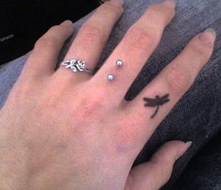 a person's hand with two rings on it and a small dragonfly tattoo