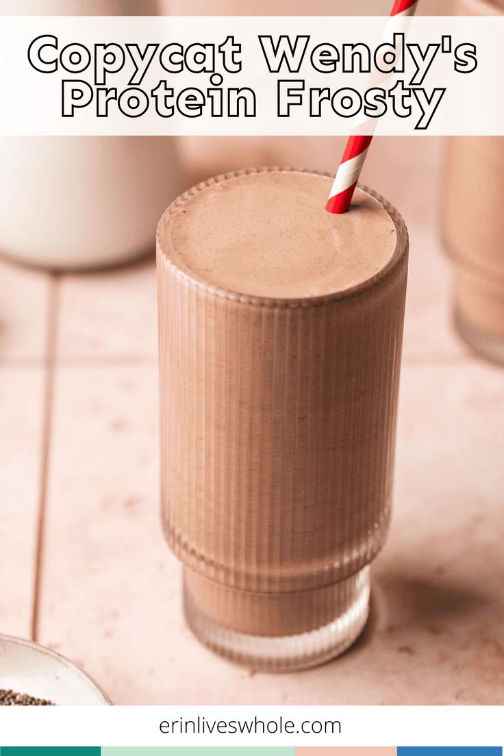 a smoothie in a tall glass with a red and white striped straw on top