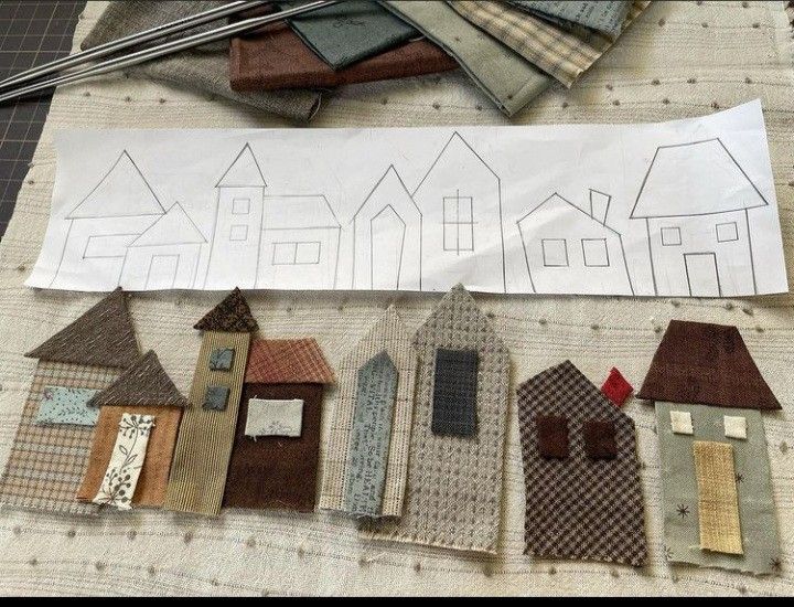 several pieces of fabric laid out on top of a table with houses drawn on them