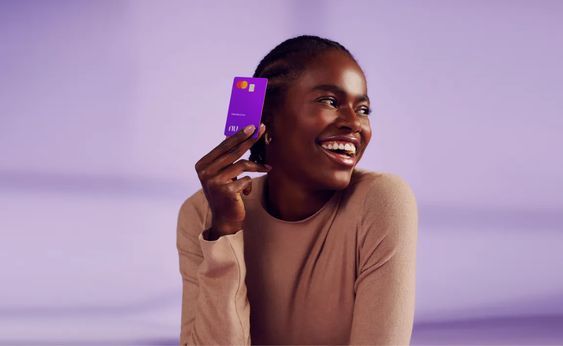 a woman holding up a purple card to her face and smiling at the camera while sitting down