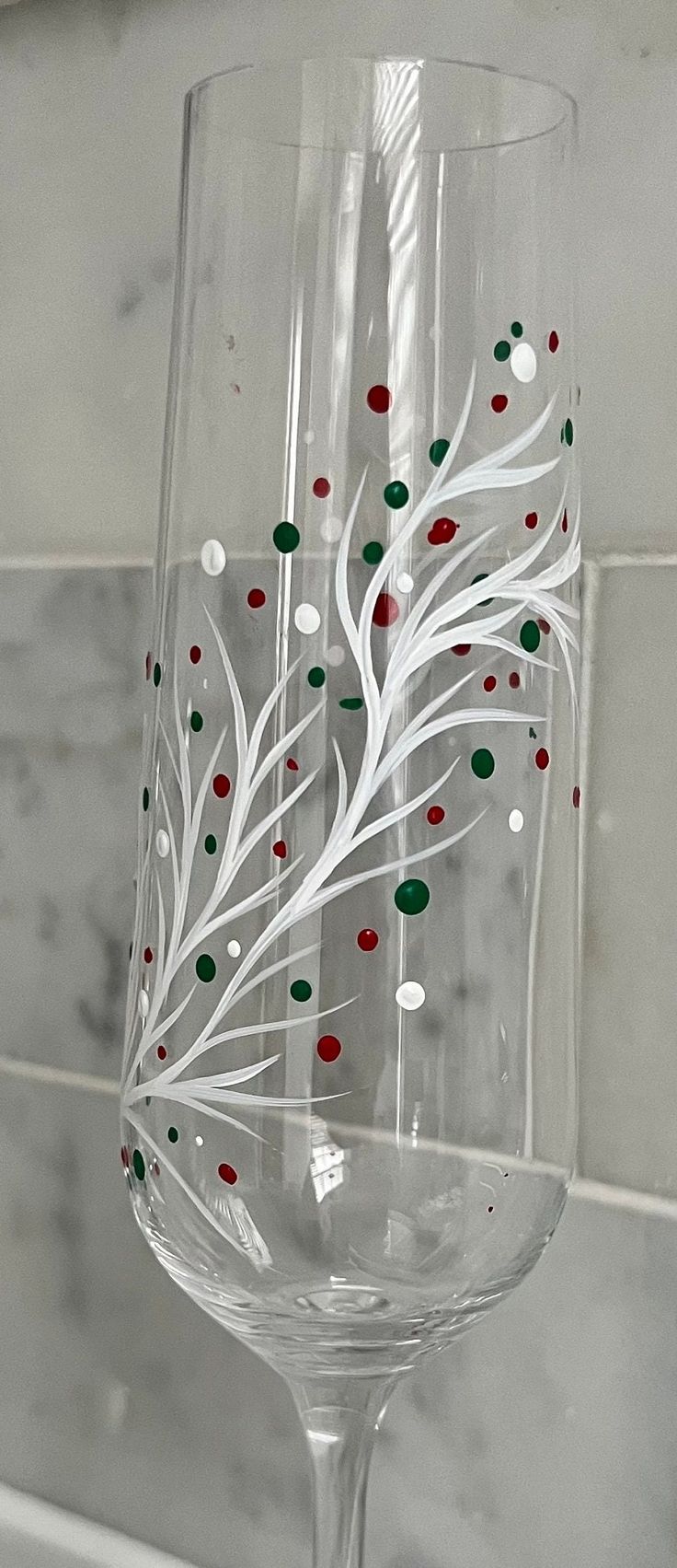 a wine glass decorated with red, green and white confetti sits on a counter