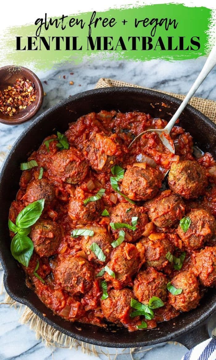 meatballs with tomato sauce in a skillet on a marble counter top next to spices and seasoning