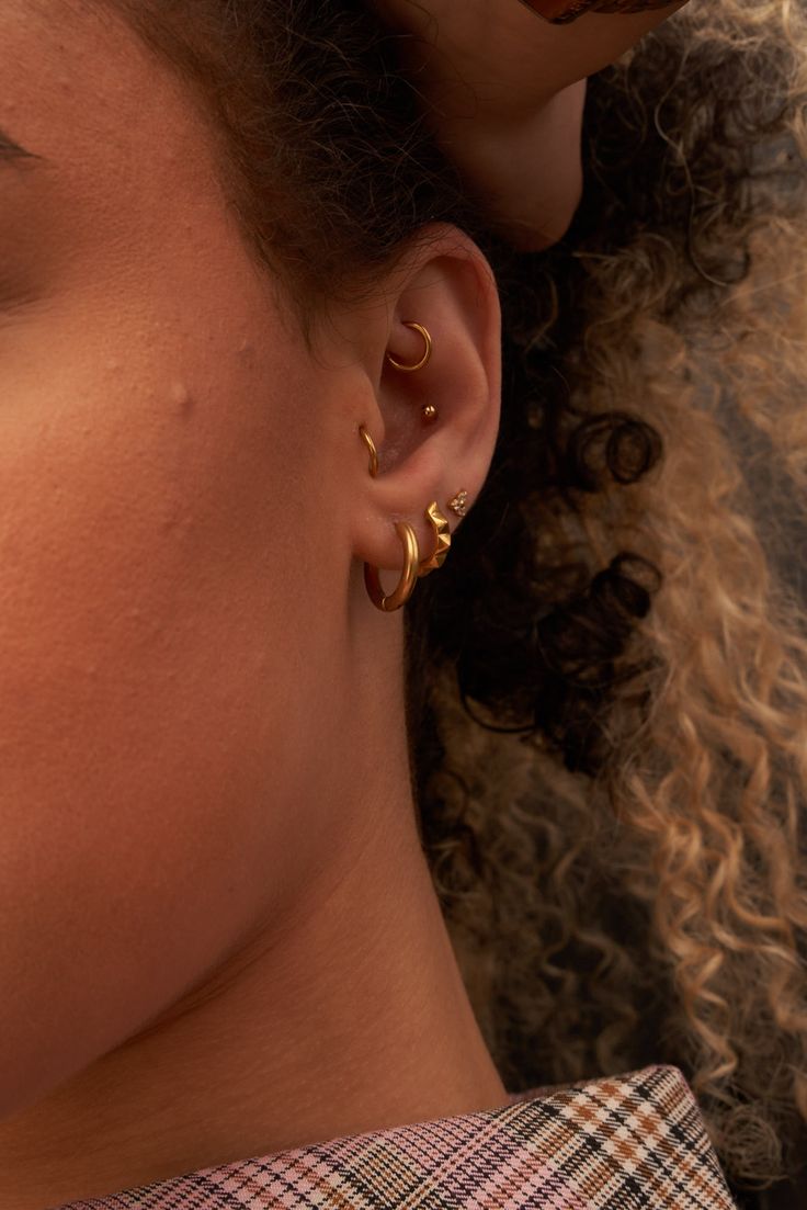 a close up of a person with ear piercings on their ears and hair in the background