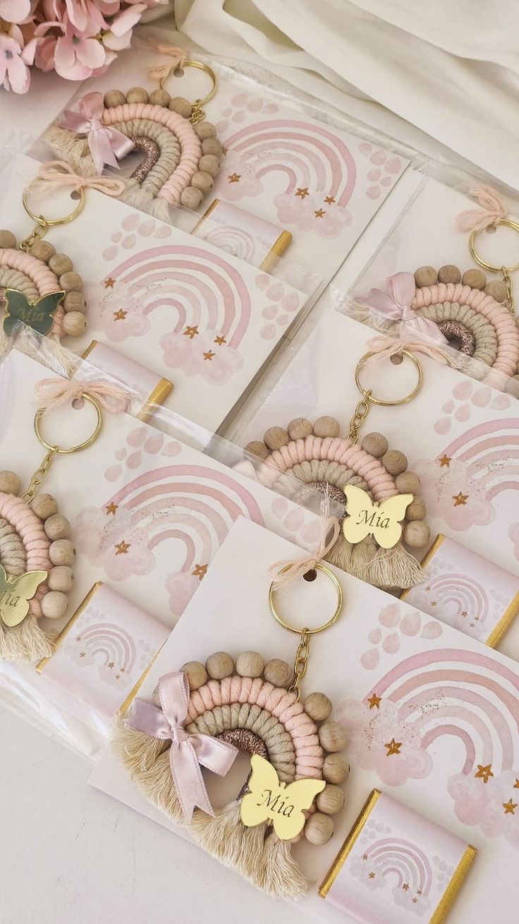 pink and gold keychains with personalized tags on them, sitting next to flowers