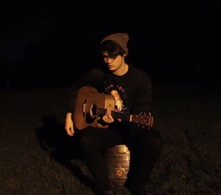 a man sitting on top of a fire hydrant holding a guitar