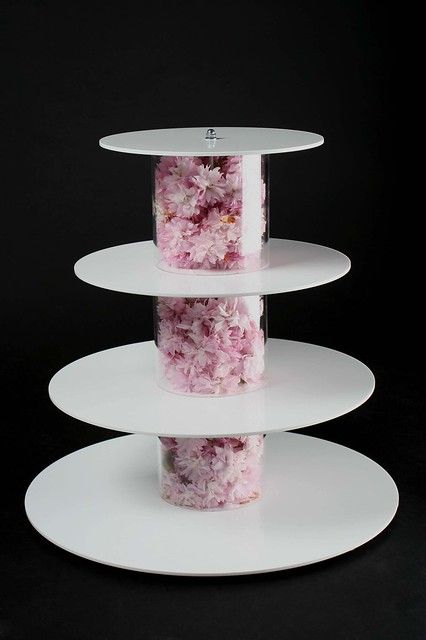 three tiered white cake stand with pink flowers on each tier and clear plastic wrap